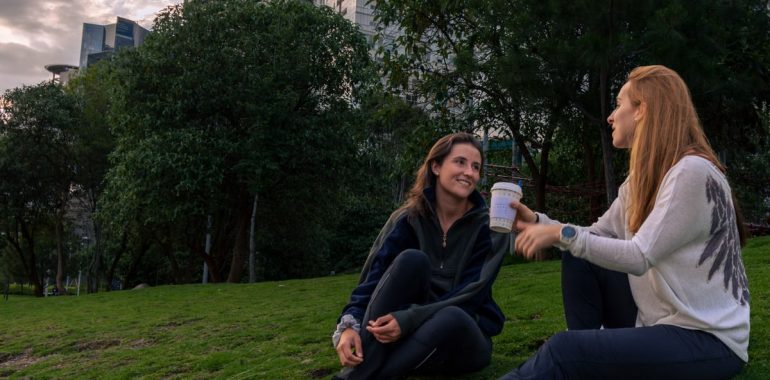 Two women enjoying coffee and conversation in a vibrant park setting in Mexico City.
