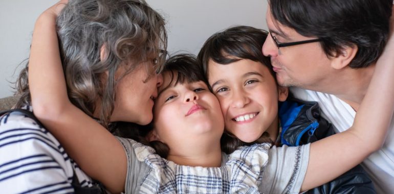A joyful family of four sharing a warm embrace, highlighting love and togetherness indoors.